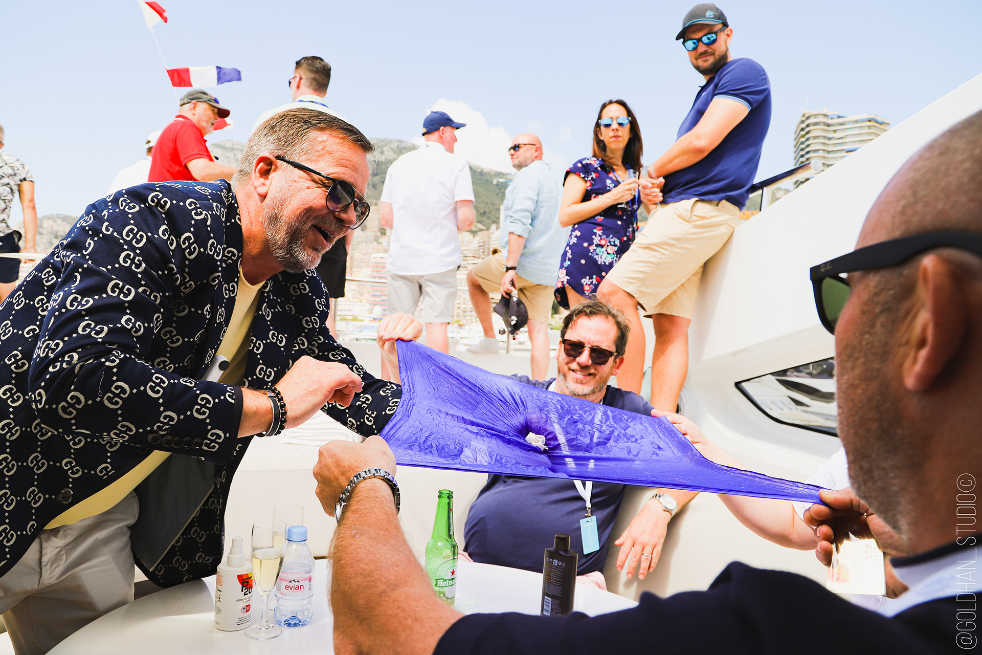 Richard Stooker seated on a yacht with guests, Monaco harbour behind